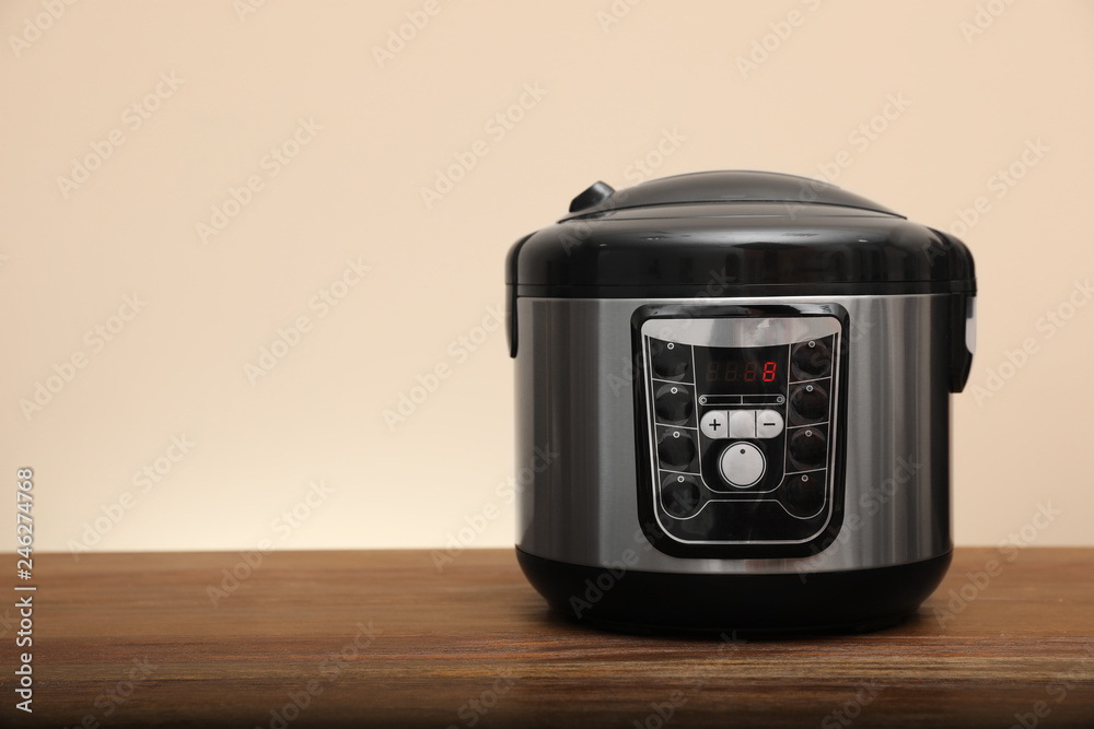 Fototapeta premium Modern electric multi cooker on table against color background. Space for text