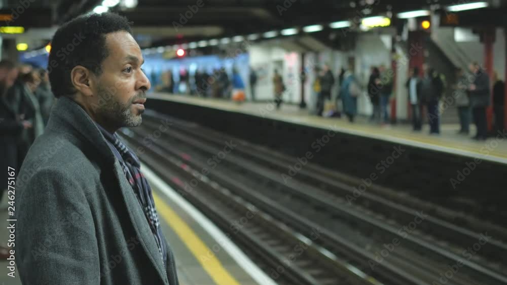 Black man waits for the train at London Underground station Black man waits for the train at London Underground station