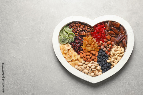 Heart shaped plate with different dried fruits and nuts on table. Space for text