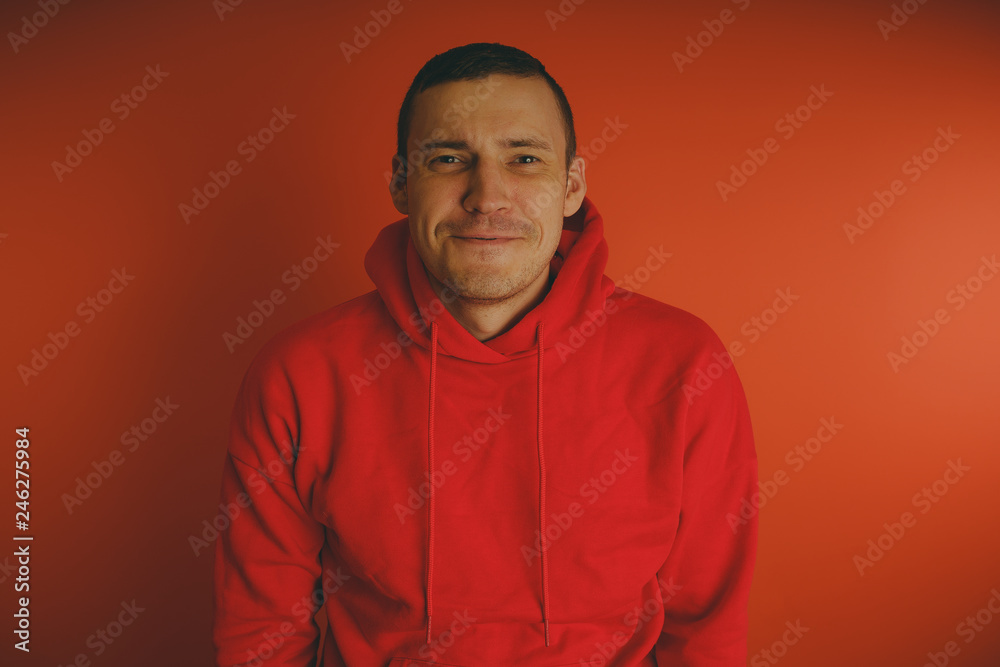Crazy and charismatic guy posing on an orange background. A man in a red tracksuit. Crazy and charismatic guy posing on an orange background. A man in a red tracksuit.