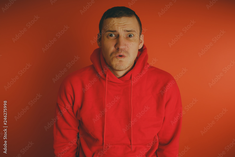 Crazy and charismatic guy posing on an orange background. A man in a red tracksuit. Crazy and charismatic guy posing on an orange background. A man in a red tracksuit.