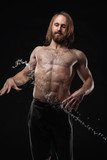 Handsome young man posing with water splashes on face and chest in Studio shot