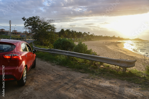 Red Rental Car Parked at Calm Beach at Sunset in Puerto Rico photo