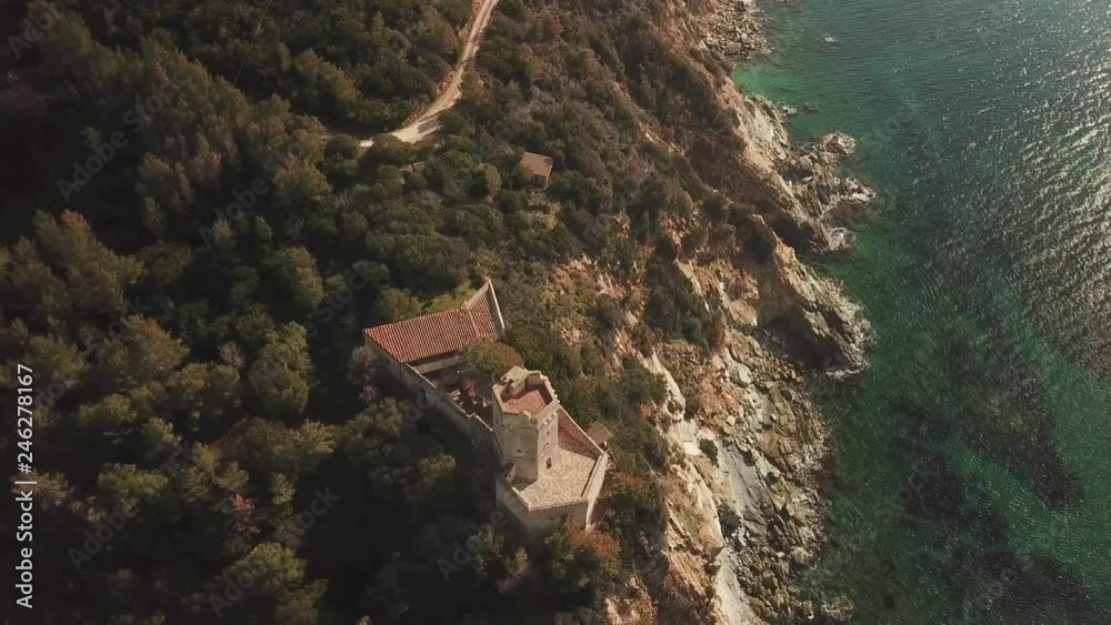 Flight over a medieval tower overlooking a cliff on a rocky coast