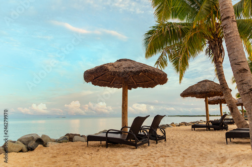 Zen scene of chaise lounge chairs on beach with thatched umbrellas and calm ocean photo