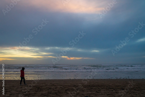 Woman waling on the beach at sunset on the Oregon coast