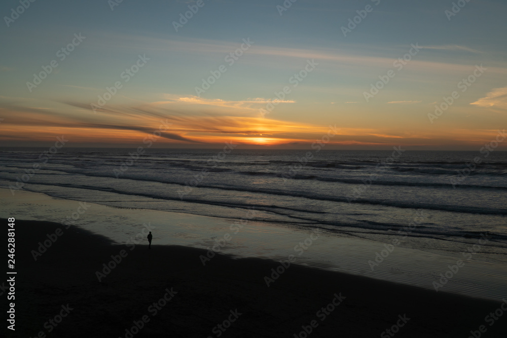 Man walking on the beach at sunset on the Oregon coast Man walking on the beach at sunset on the Oregon coast