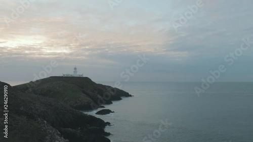 Wide view of lighthouse above sea on cloudy evening. Strumble Head Lighthouse. photo