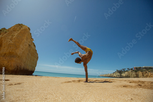 young happy African man on ocean shore doing capoeira and enjoying sunny day and summer holiday. Dark skin, mixed race