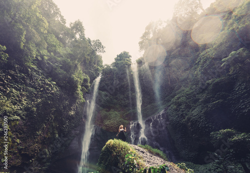 Young woman walking near jungle waterfall