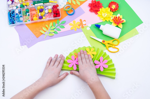 Child makes a gift to mother for the holiday of spring. Flower glued from paper.