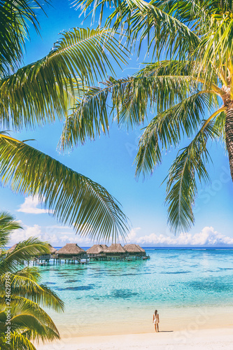 Tahiti luxuy travel resort overwater bungalow hotel in Bora Bora idyllic holiday woman in paradise vertical background with copy space on palm trees.