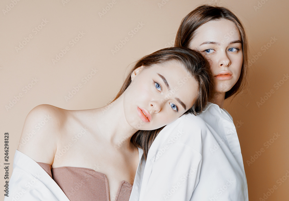 Fashion beauty models two sisters twins beautiful nude girls looking at the  camera isolated on beige background Stock Photo