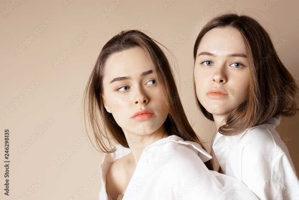 Fashion beauty models two sisters twins beautiful nude girls looking at the  camera isolated on beige background Stock Photo