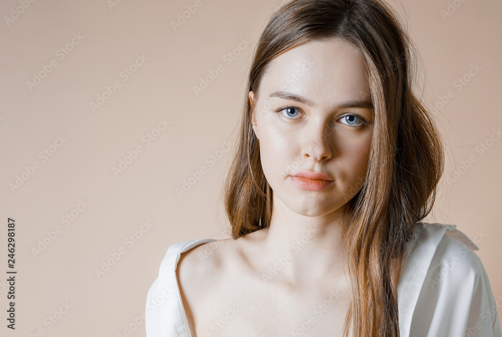 Fashion model beauty nude girl in white shirt looking at the camera isolated on beige background Fashion model beauty nude girl in white shirt looking at the camera isolated on beige background