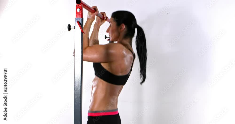 Strong fit Caucasian woman doing pull ups in a gym.