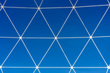 Metal white lattice in the form of geometric shapes on a background of blue sky