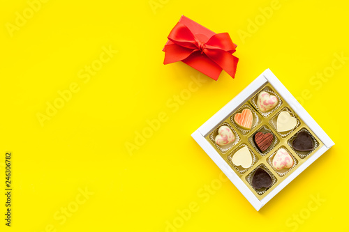 Sweets for Valentine's day near red gift box on yellow background top view space for text