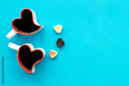 Dating on Valentine's day concept. Heart-shaped mugs and sweets on blue background top view copy space