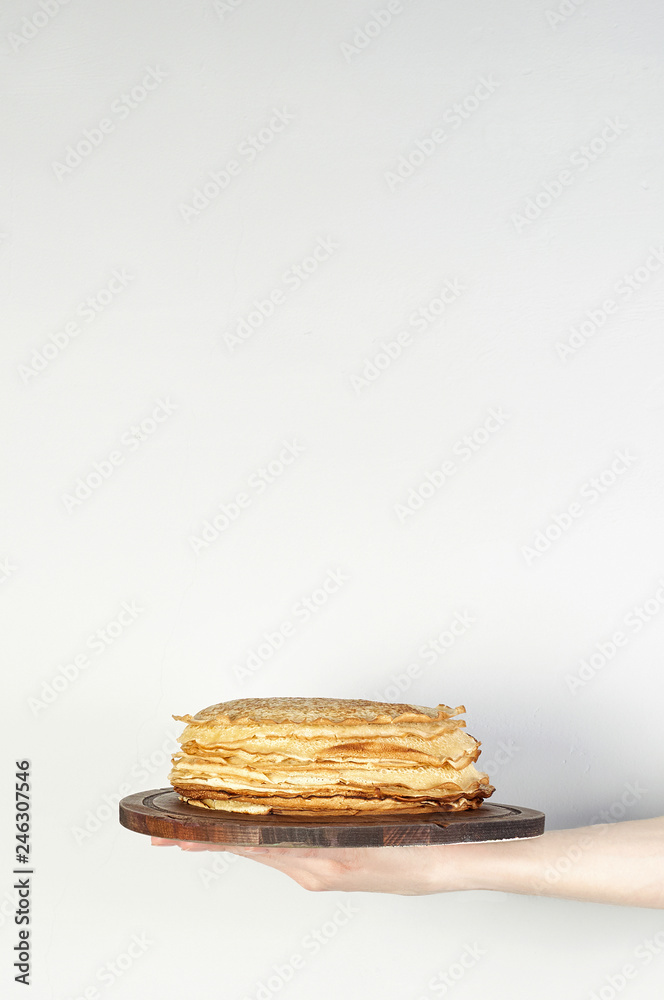 Stack of russian pancake blini in rustic wooden dish woman holds in hands