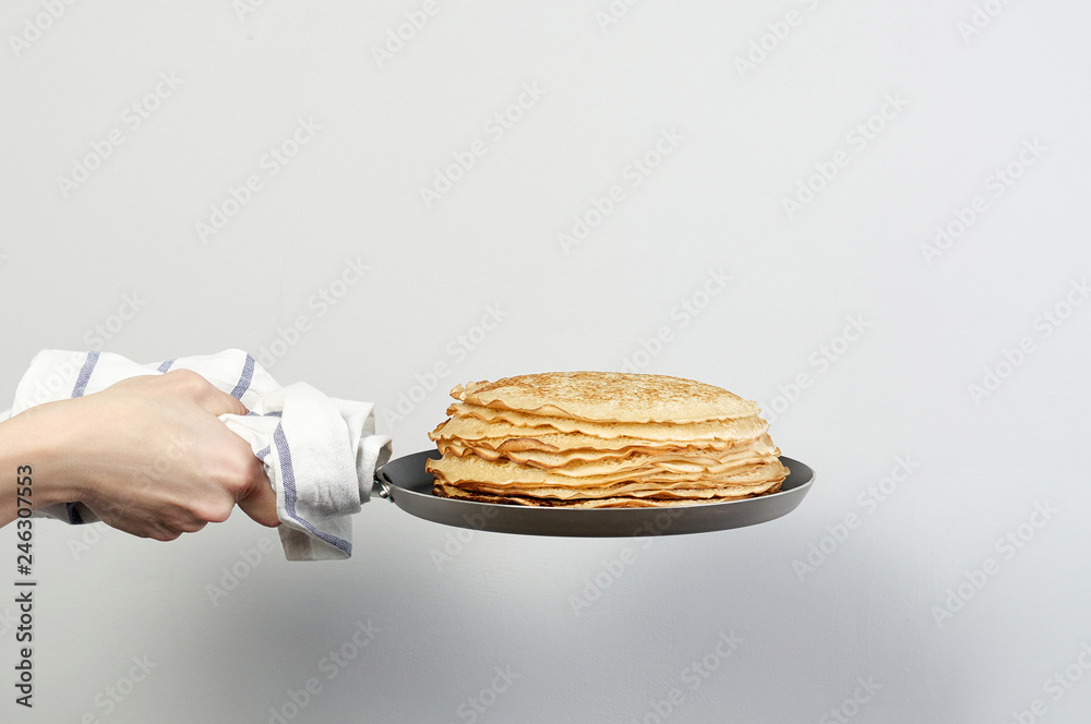 Stack of russian pancake blini in pan woman holds in hands