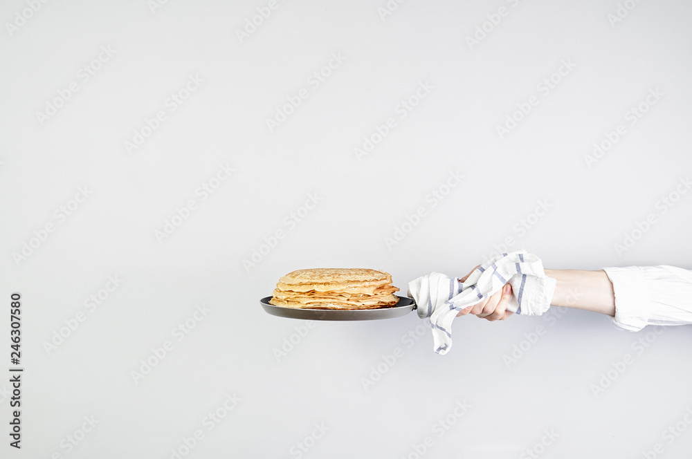 Stack of russian pancake blini in pan woman holds in hands