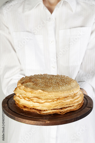 Stack of russian pancake blini in rustic wooden dish woman holds in hands