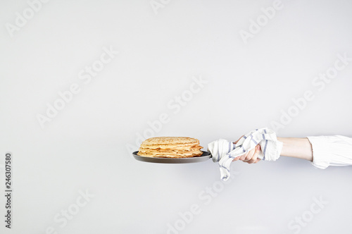 Stack of russian pancake blini in pan woman holds in hands