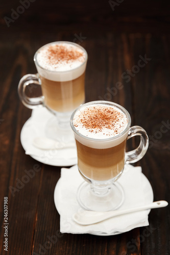 Coffee in glass on the wooden background. A glass with cappuccino and cinnamon. 