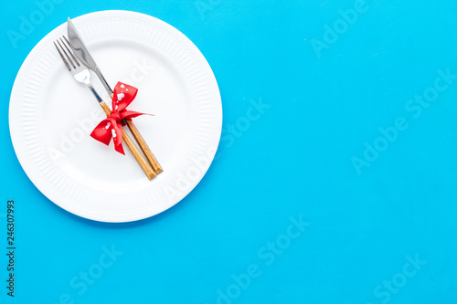 Dating on Valentine's day concept. Festive dishes, tableware on plate on blue background top view space for text