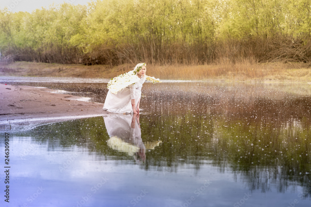 Nice blonde girl with white flower wings near river Nice blonde girl with white flower wings near river