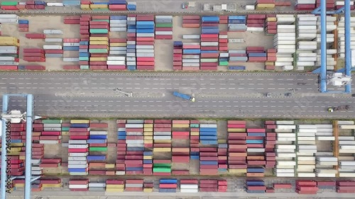 Transtainer yard - Various brands and colours of Shipping containers stacked by Transtainers (Mobile gantry cranes) off of service trucks - Top down aerial footage. photo