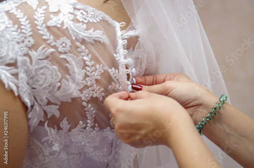 Woman laces up corset on bride's waist. Morning bride concept