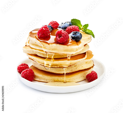 Delicious pancakes with berries, honey or maple syrup. Homemade pancakes and sweet syrup on white plate isolated. photo