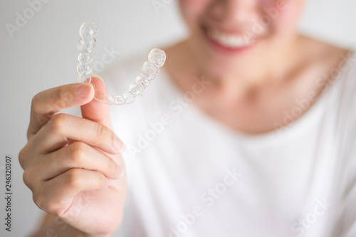 A smiling woman holding invisalign or invisible braces, orthodontic equipment