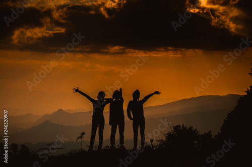 The silhouette of a woman watching the sunset with a mountain view in the evening Of the mountain team Leadership concept