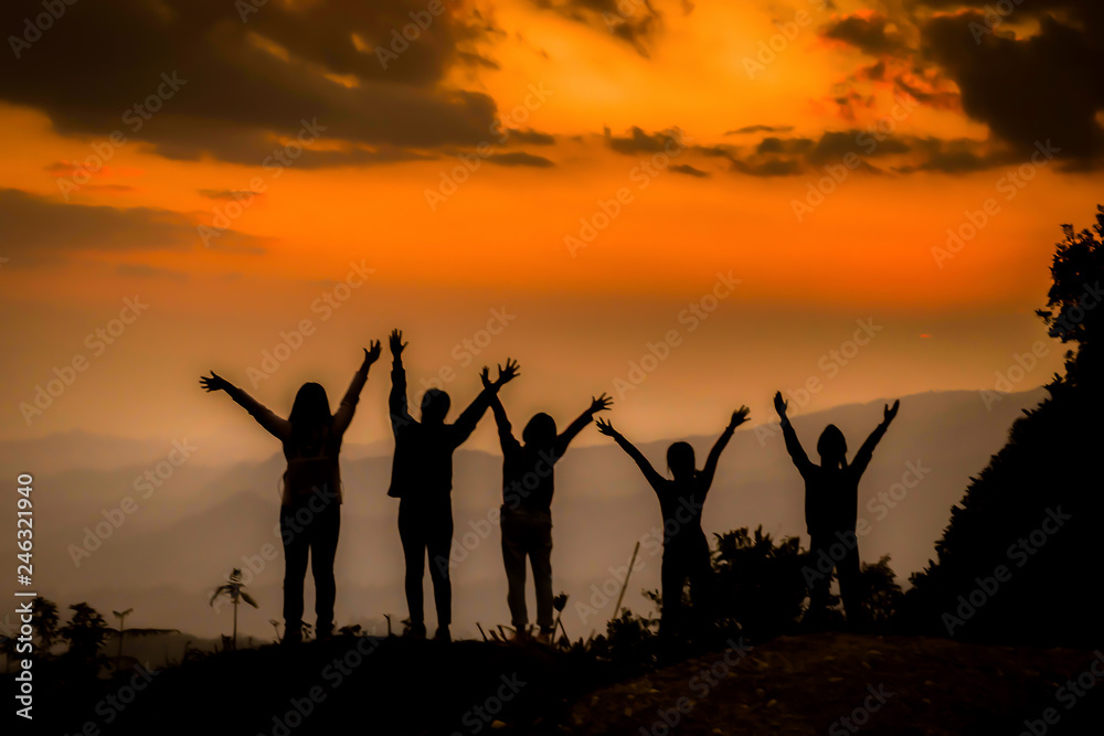 The silhouette of a woman standing watching the sunset sky Darling pointed to the cloud Colorful sky, orange sky and golden sky Queue of close friends