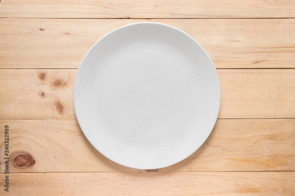 Empty white round dish or plate on wooden background, top view of tableware with copy space Empty white round dish or plate on wooden background, top view of tableware with copy space