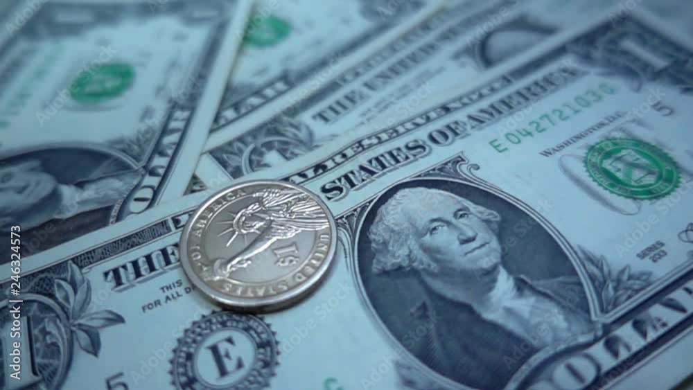 Slow motion of one dollar coin rotates on a one dollar bills Slow motion of one dollar coin rotates on a one dollar bills