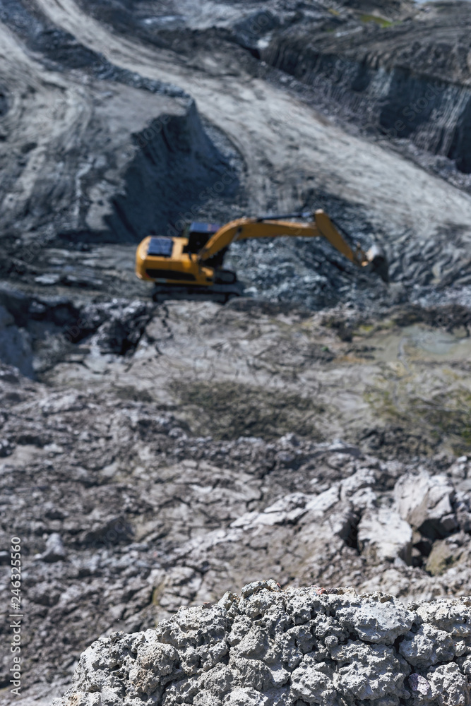 view from the hill to the excavator, working far below. Selective focus view from the hill to the excavator, working far below. Selective focus