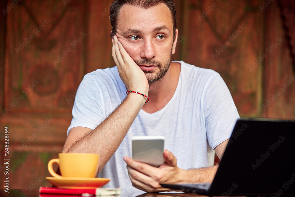 Man with smartphone, coffee / tea and laptop on a home porch. Man with smartphone, coffee / tea and laptop on a home porch.