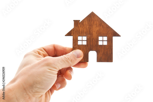 Man's hand holds wooden flat house on the white background