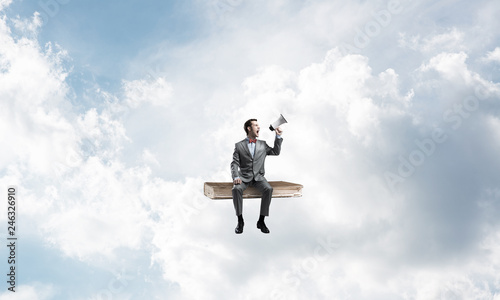 Businessman floating in blue sky and announcing something in loudspeaker © adam121