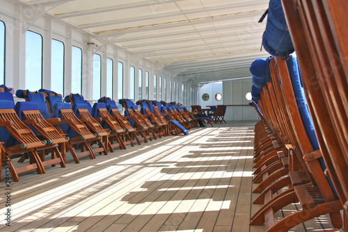 Hölzerne Sonnenliegen auf Luxuskreuzfahrtschiff Wooden teak deck chairs or sun loungers on outdoor pool deck of luxury cruiseship or cruise ship liner Deutschland photo