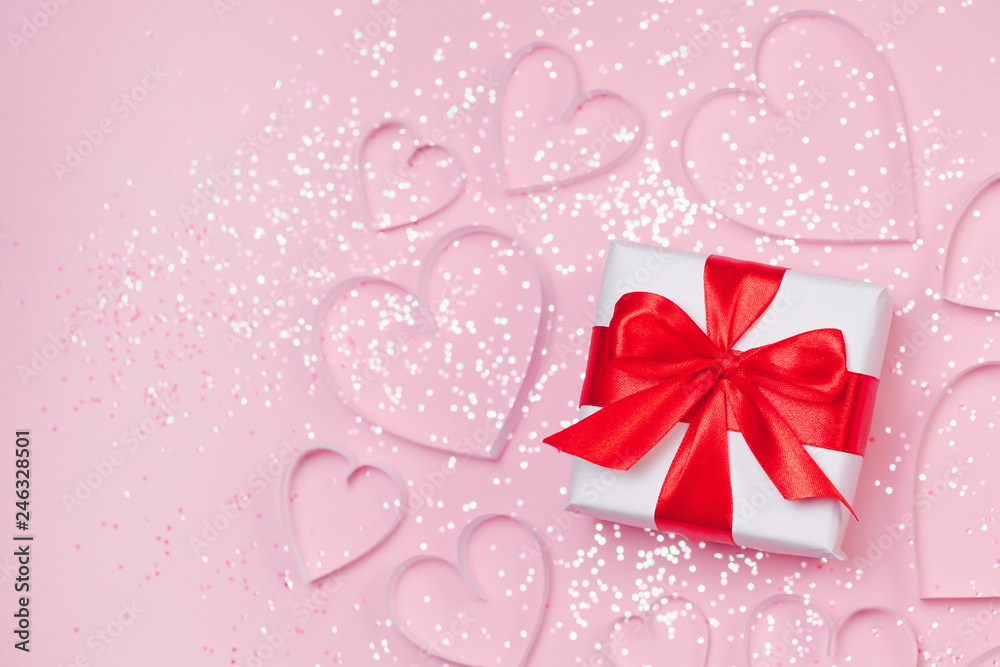 Pink holiday Valentine's background with present gift box and little hearts on background. Valentine's day greeting concept. Top view, flat lay.