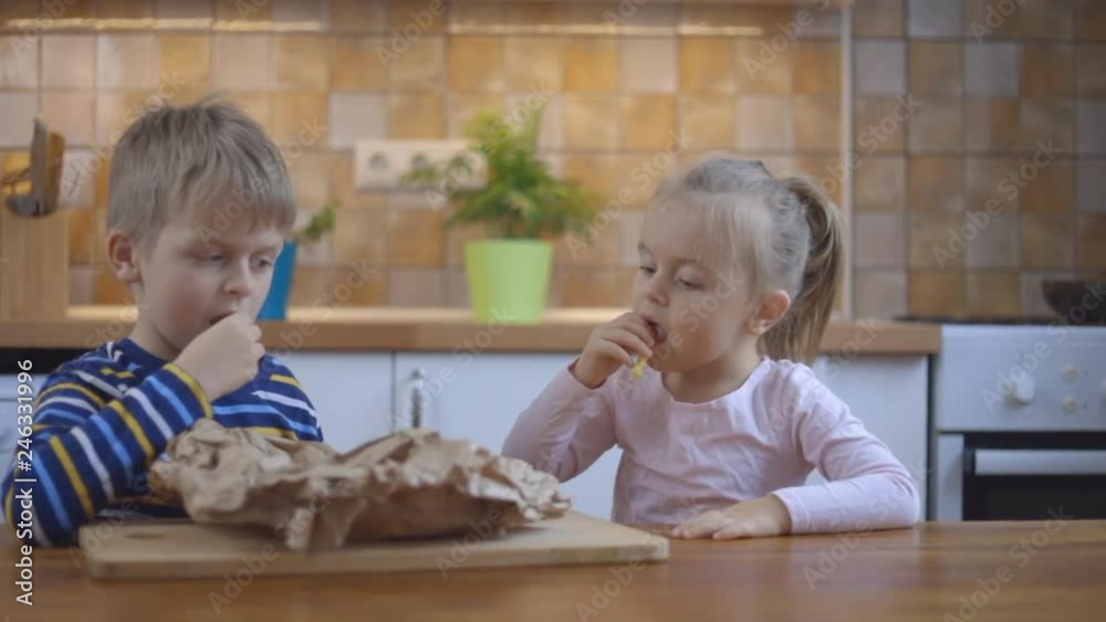 Little boy and cute girl eating french fries at home Little boy and cute girl eating french fries at home