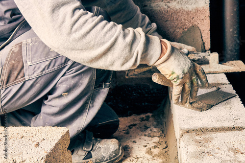 Real construction worker bricklaying the wall indoors.