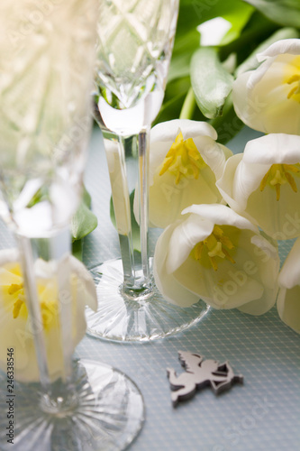 Two glasses with champagne and tulips on a blue background