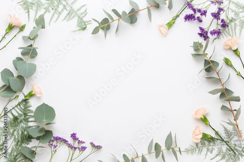 Flowers composition. Paper blank, carnation flowers, eucalyptus branches on pastel  background. Flat lay, top view, copy spaceFlat lay stiil life.