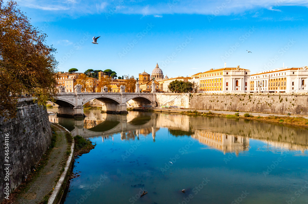 Tiber river streams, Ponte Vittorio Emanuele II bridge, flying seagulls and Rome cityscape view with St. Peter dome on the background